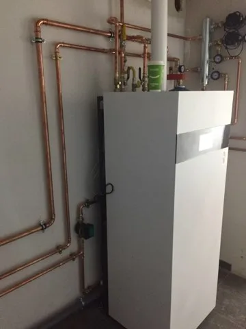 Instalacja hydrauliczna z piecem gazowym i rurami miedzianymi, wykonana w pomieszczeniu technicznym